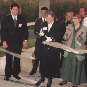 Carol and Joel ribbon cutting ceremony surrounded by friends and family